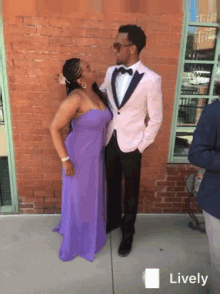 a man in a pink tuxedo and a woman in a purple dress pose for a photo