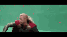 a man in a superhero costume is running on a green background .