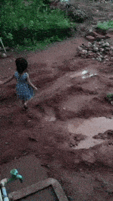 a little girl is playing in a muddy puddle