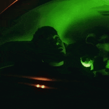 a man is sitting in a car with green lights behind him