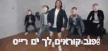 a group of people are dancing in front of a wall with hebrew writing