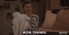 a woman in a tie dye sweater is holding a white blanket and says wow thanks