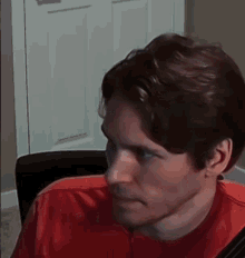 a close up of a man 's face with a red shirt on