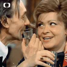 a man kisses a woman on the cheek while holding a glass