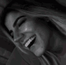 a woman is smiling in a black and white photo with a blurred background