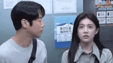 a man and a woman are looking at each other in front of a sign that says ' i 'm sorry '