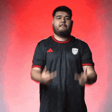 a man with a beard wearing a black adidas shirt is clapping his hands