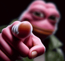 a pink frog pointing at the camera with a black background