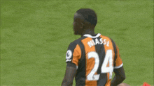 a soccer player wearing a black and orange jersey with the number 24 on the back