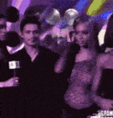 a woman in a purple dress is standing in front of a man holding a microphone with the number 1 on it
