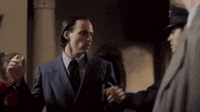 a man in a suit and tie is talking to another man