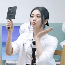 a woman in a white shirt and tie is holding a mirror with a drawing of a gorilla on it