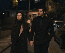 a man and a woman holding hands on a street