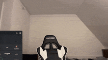 a black and white s-racer gaming chair in front of a computer screen