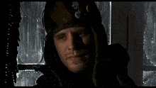 a person wearing a mask is standing in front of a window in the rain