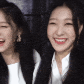 two women are smiling for the camera and one is wearing a necklace