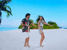 a man and woman are dancing on a sandy beach