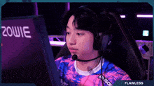 a man wearing headphones and a shirt that says flawless looks at a computer screen