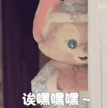 a stuffed animal is peeking out from behind a wall and making a face .