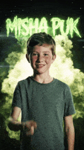 a young boy stands in front of a poster that says " misha puk "