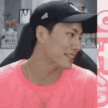 a man wearing a pink shirt and a black hat is smiling while sitting in a chair .