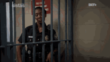 a female police officer behind bars in a jail cell with a bet advertisement in the background