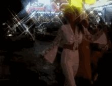 a woman in a white dress is dancing in a dark room with a band playing in the background