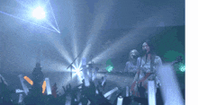 a woman singing into a microphone while holding a guitar in front of a crowd