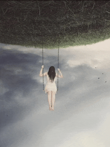 a woman in a white dress is swinging in the sky