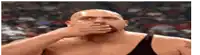 a bald man is covering his mouth with his hand in a wrestling match .
