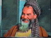a man with a beard wearing a turban and scarf smiles