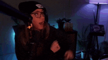 a woman wearing a beanie and glasses is dancing in a dark room