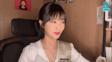 a woman is sitting in a chair in front of a wall with a vlive logo on it .