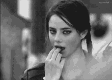 a black and white photo of a woman licking her lips .