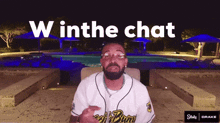 a man sitting in front of a pool with the words " w in the chat " on the bottom