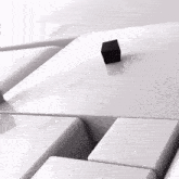 a black cube is on top of a white surface