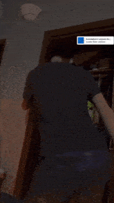 a man in a black shirt is standing in a closet with clothes hanging on hooks