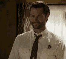 a man wearing a white shirt and tie has a badge on his pocket