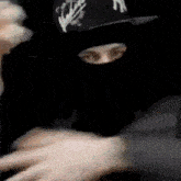 a man wearing a mask and a hat is hugging another man in a room .