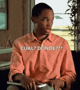 a man in a pink shirt is holding a book and says cual donde??