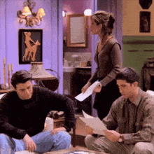 a group of people are sitting on a couch looking at papers