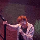 a man is singing into a microphone while standing on a set of stairs
