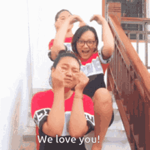 two girls are sitting on a set of stairs with the words we love you