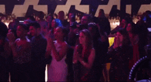 a crowd of people are dancing in a dark room with purple lights .