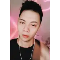 a young man wearing headphones looks at the camera with a pink background