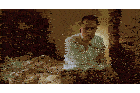 a man in a white shirt sits on a bed with his arms crossed