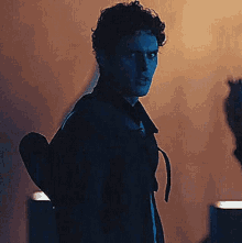 a man is standing in a dark room holding a heart in his hand .