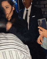 a man in a suit and tie is standing next to a woman holding a cell phone