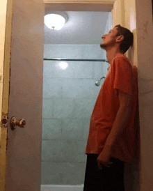 a man in a red shirt is standing in a bathroom