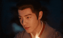 a close up of a man 's face with a candle in his hand in the dark .